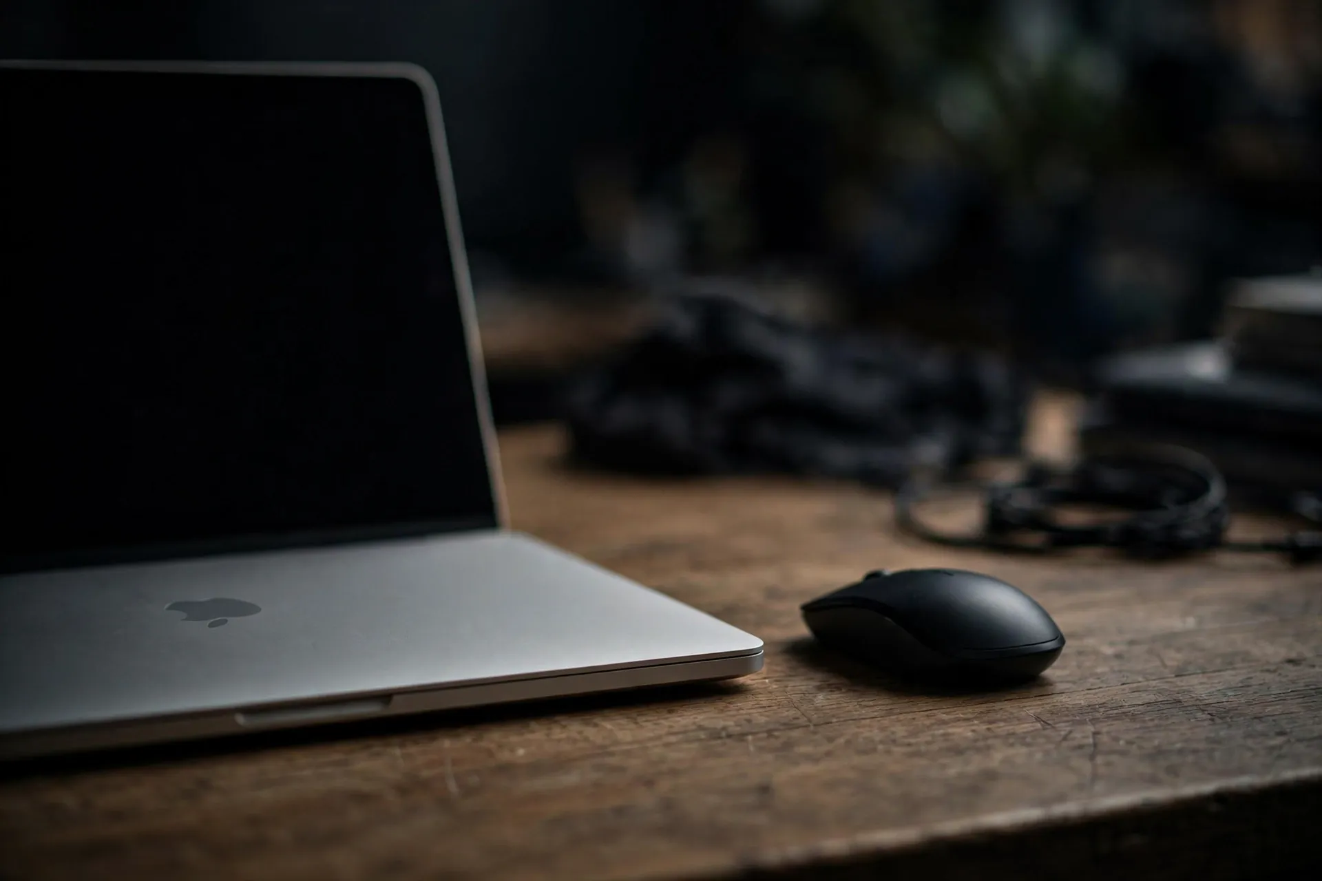 MacBook beside a mouse on a wooden desk